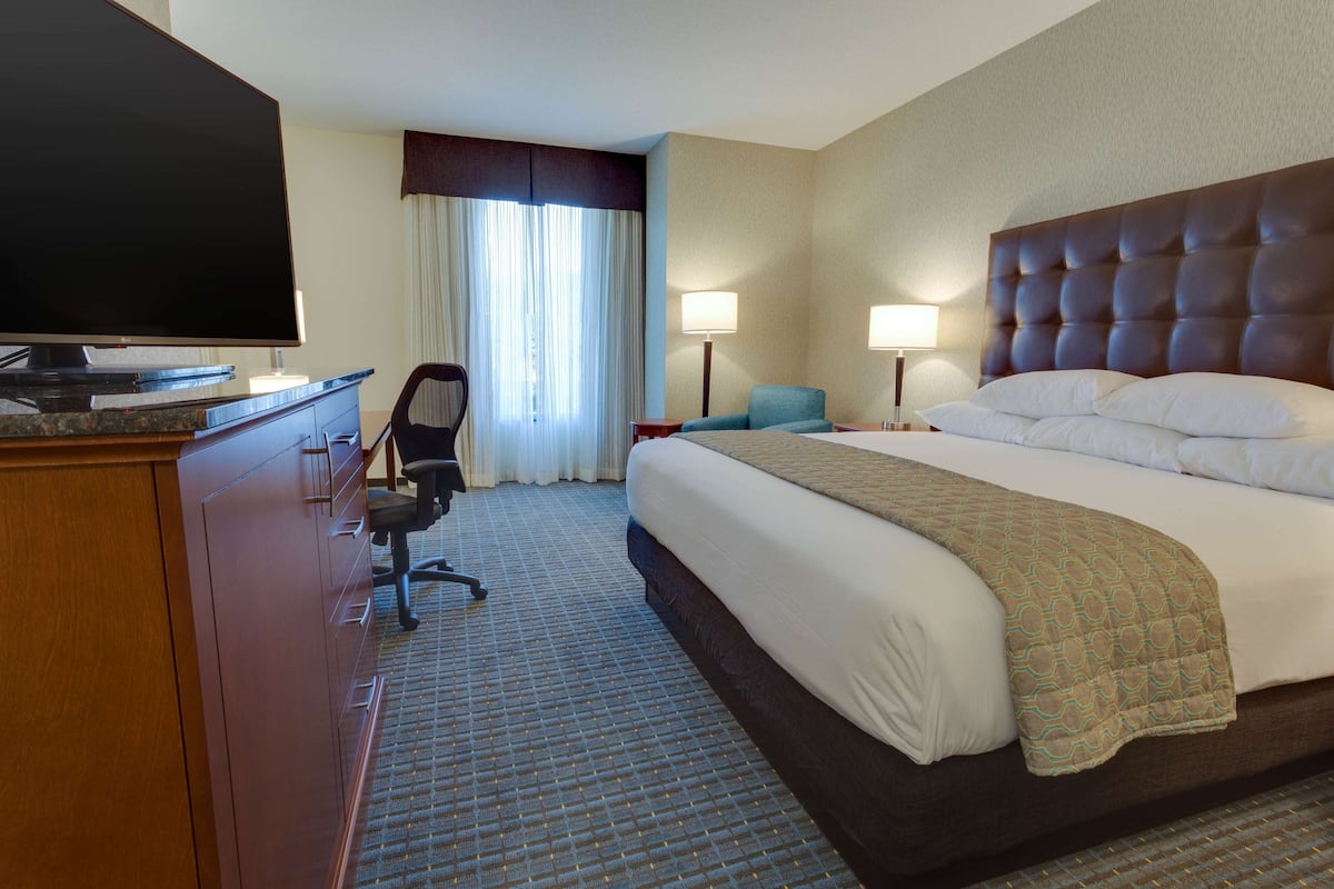 A hotel room with a large bed, a flat-screen TV, a desk, and a chair.