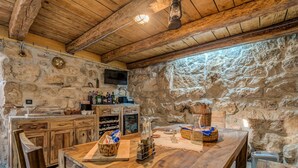 Une cuisine rustique avec des murs en pierre, des poutres en bois, une table à manger en bois et une cheminée en pierre.