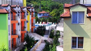 A row of colorful apartment buildings with balconies, a clear sky, and a hillside in the background. - Large Deluxe Studio in MiniSmart RedZebra Complex (Balchik)