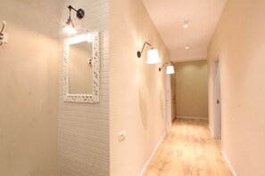 Stunning hallway with a door at the end, flanked by light fixtures and a wooden floor.