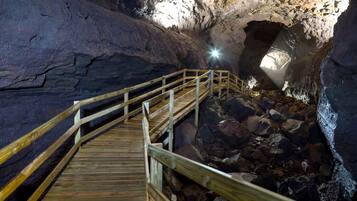 Una escalera de madera que conduce a una cueva, con una fuente de luz natural en la parte superior.
