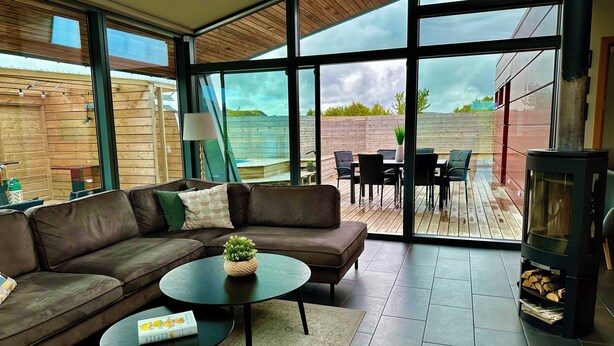 A modern living room with a leather sofa, a round coffee table, and a fireplace. - Luxury, Modern, Amazing River/Mountain view with Hot Tub. Winter/Summer Holiday (Bifröst)