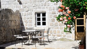 A stone building with a window and a table with chairs. - Charming stone house in Cavtat old town (Cavtat)