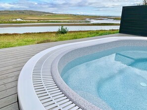 A hot tub with a wooden deck and a view of a river and hills. - Brún Golden Circle Villa, Private Hot Tub & River Views, Walk to Laugarás Lagoon (Selfoss)