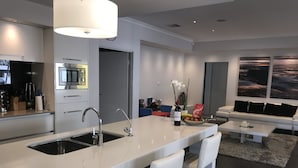 A modern kitchen with a central island, stainless steel appliances, and a dining area with a sofa and coffee table. - Magnificent Beach Retreat (Alkimos)