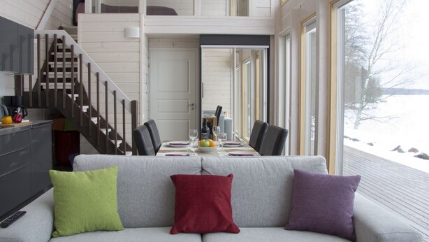 Un interior moderno con zona de comedor, sofá y escalera.