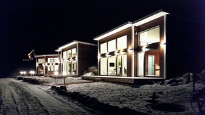Un edificio moderno con grandes ventanales y una entrada bien iluminada, en un paisaje nevado.