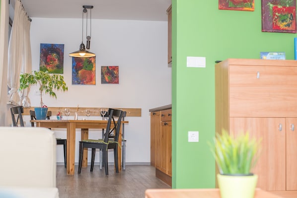A dining area with a wooden table, chairs, and a hanging light fixture.