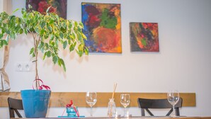 Une table à manger avec un pot bleu, deux verres à vin, une bougie et un petit objet décoratif.