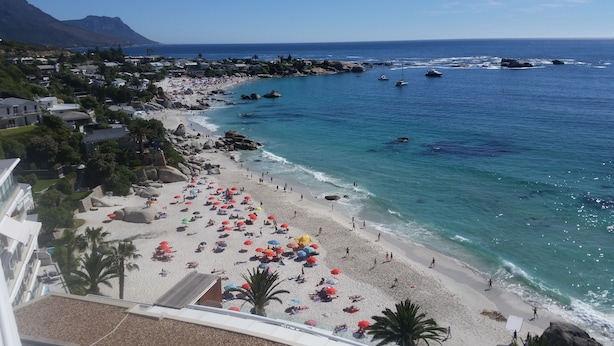 Une plage offrant une vue dégagée sur l’océan et les bateaux, entourée d’immeubles et de palmiers.