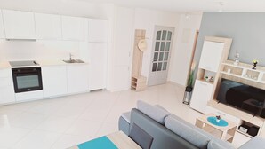 A modern kitchen with white cabinets, a built-in oven, and a dining area with a table set for two. - Enelani 2 apartment near the beach_outdoor gym/table tennis/table football (Kaštel Štafilić)