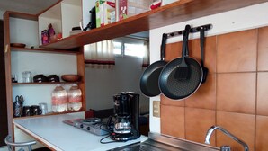 A compact kitchen with a gas stove, a coffee maker, and hanging pots. - Casa La Joya in Down Town- Santo Domingo Church (Oaxaca)