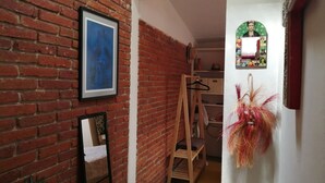 A narrow hallway with a brick wall, a wooden ladder, a mirror, and a hanging plant. - Casa La Joya in Down Town- Santo Domingo Church (Oaxaca)