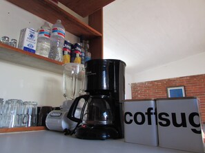 A kitchen with a coffee maker, a refrigerator, and various kitchen items on the counter.