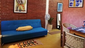 A living room with a blue sofa, a wicker chair, a small table, and a fan. - Casa La Joya in Down Town- Santo Domingo Church (Oaxaca)