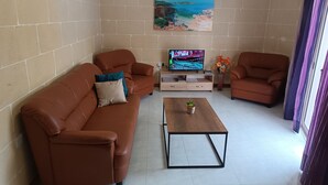 A living room with a brown leather sofa, a wooden coffee table, and a television on a wooden stand.