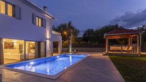 A modern house with a swimming pool, a covered patio, and a well-lit interior. - Beautiful Eco-Friendly Villa in Split – Just Steps from Marjan and the Center (Split)