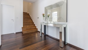 A modern interior with a wooden staircase, a glass console table, and a large mirror. - Beautiful Eco-Friendly Villa in Split – Just Steps from Marjan and the Center (Split)