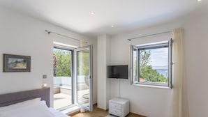 A modern bedroom with a bed, a TV, a nightstand, and a view of the outdoors. - Beautiful Eco-Friendly Villa in Split – Just Steps from Marjan and the Center (Split)