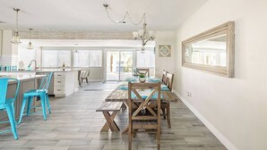 A spacious kitchen with a wooden dining table, blue chairs, and a large window. - L2 EV, Modern Home With Putting Green, Pool, Spa, Pet Friendly, Split Floorplan (Scottsdale)