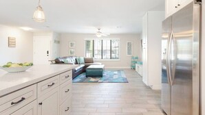 A modern kitchen with a large refrigerator, a dining area with a sofa, and a kitchen island with drawers. - L2 EV, Modern Home With Putting Green, Pool, Spa, Pet Friendly, Split Floorplan (Scottsdale)