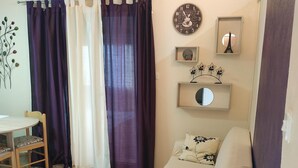A cozy living room with a sofa, a dining table with chairs, a cowhide rug, and a wall clock.