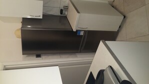 A kitchen with a refrigerator, a microwave, and a coffee maker on the counter.