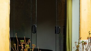 A sliding glass door with a potted plant on the left and another on the right. - Beautiful house with garden in historic center Cusco (Cusco)