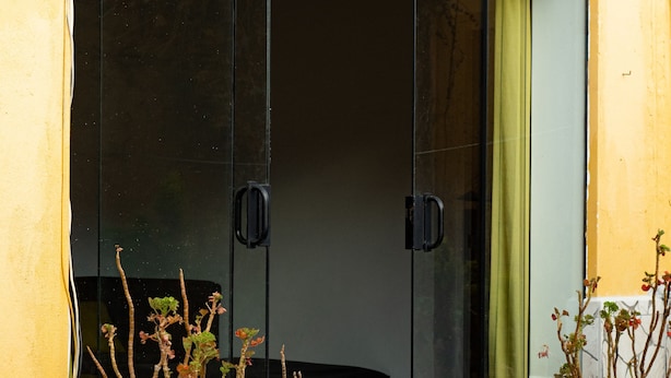 A sliding glass door with a potted plant on the left and another on the right. - Beautiful house with garden in historic center Cusco (Cusco)