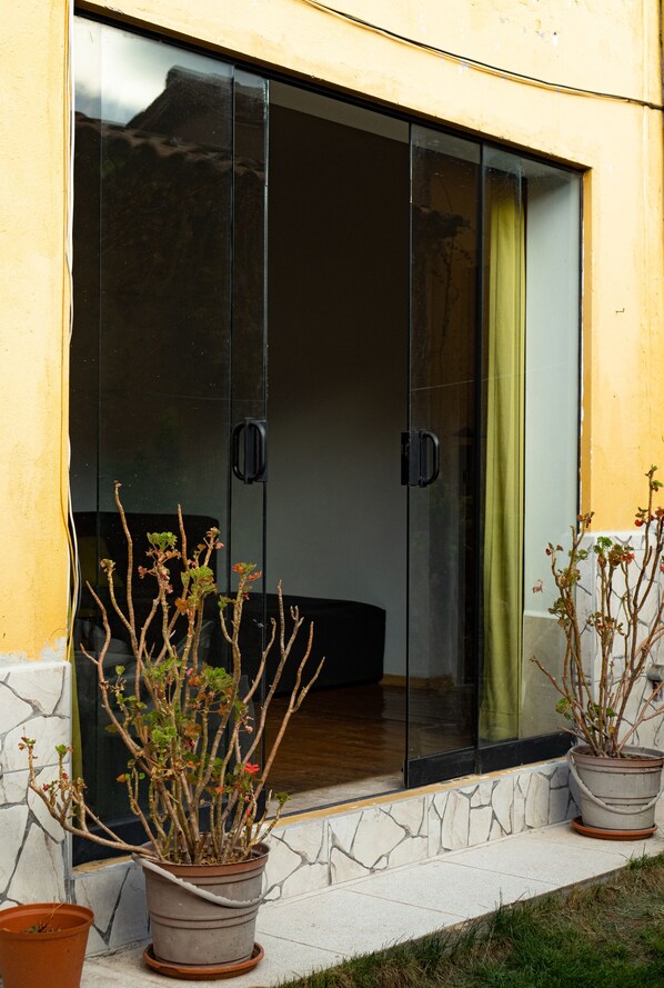 A sliding glass door with a potted plant on the left and another on the right. - Beautiful house with garden in historic center Cusco (Cusco)