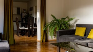 A living room with a sofa, a coffee table, and a dining area with chairs and a table. - Beautiful house with garden in historic center Cusco (Cusco)