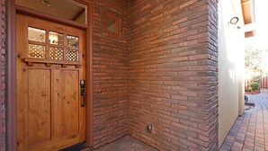 Une porte en bois avec un panneau de verre et un coin de mur en briques.