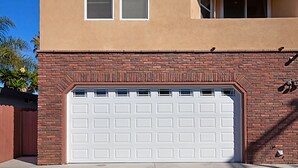 Une porte de garage avec une façade en briques et un ciel dégagé en arrière-plan.