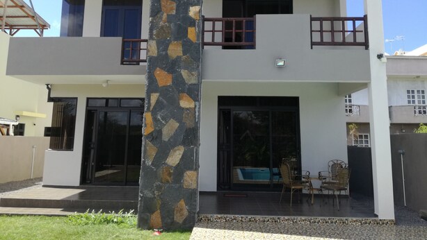 A two-story house with a stone pillar, large windows, and a balcony. - Luxury villa with 4 bedroom all en-suite and private swimming pool, with seaview (Pointe Aux Biches)