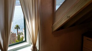 Ett rum med utsikt över en vattenyta och en avlägsen byggnad.