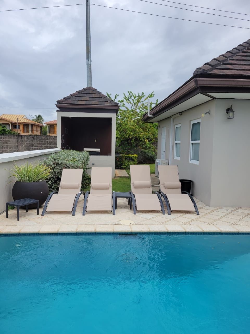 A swimming pool with lounge chairs and a barbecue area.