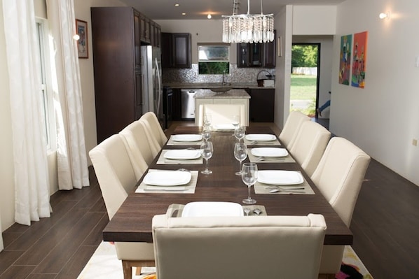 Een eetkamer met een lange tafel gedekt voor zes personen, omringd door comfortabele stoelen.