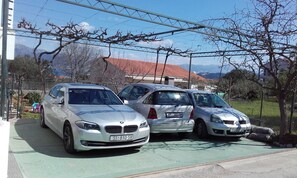 Three parked cars in a driveway with a mountain view in the background.