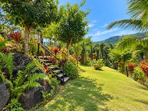 Ein Garten mit einer Treppe, umgeben von üppiger Bepflanzung und tropischen Pflanzen.