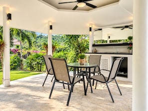 An outdoor patio with a round table and chairs, a ceiling fan, and a kitchen area with a sink and countertop. - Luxury Private pool Villa Nap Dau Perfect for Groups (Chalong,Tambon Wichit)