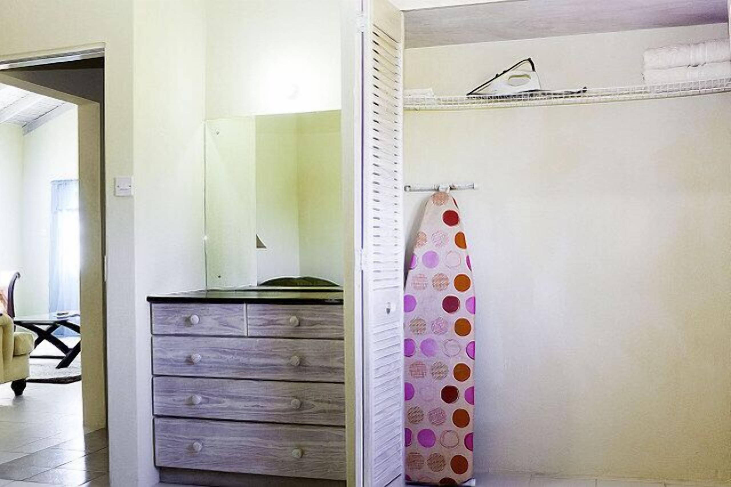 Un baño con un aparador de madera, una cortina de ducha con estampado de lunares y un perchero.