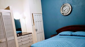 Un dormitorio con cama, armario, cómoda y un reloj de pared.