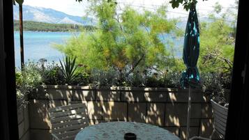 A patio with a round table and chairs, overlooking a body of water and mountains.