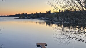 A calm lake with a wooden dock extending into the water, surrounded by a grassy area and a fence. - Premier Chalet Home on Beautiful Williams Lake - Consistently #1 in Region.  (Cheney)