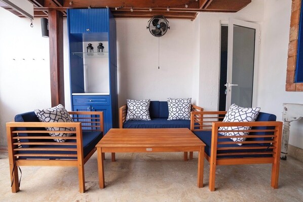 A room with a wooden sofa set, a blue cabinet, and a ceiling fan. - Beautiful Beach Condo vacation rental in Las Terrenas in Balcones del Atlántico. (Las Terrenas)