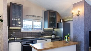 Een moderne keuken met een centraal kookeiland, ingebouwde apparatuur en een raam met uitzicht op de stad.