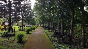 A pathway lined with trees and a playground with yellow and red equipment. - Tagaytay Summer House (Tagaytay)
