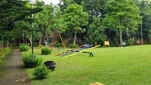 A park with a grassy area, playground equipment, and a pathway. - Tagaytay Summer House (Tagaytay)