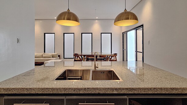 A kitchen with granite countertops, a double sink, and pendant lighting. - Tagaytay Summer House (Tagaytay)