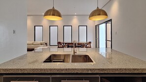 A kitchen with granite countertops, a double sink, and pendant lighting. - Tagaytay Summer House (Tagaytay)